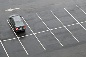 Single car in empty parking lot Single car in otherwise empty parking lot, in the rain